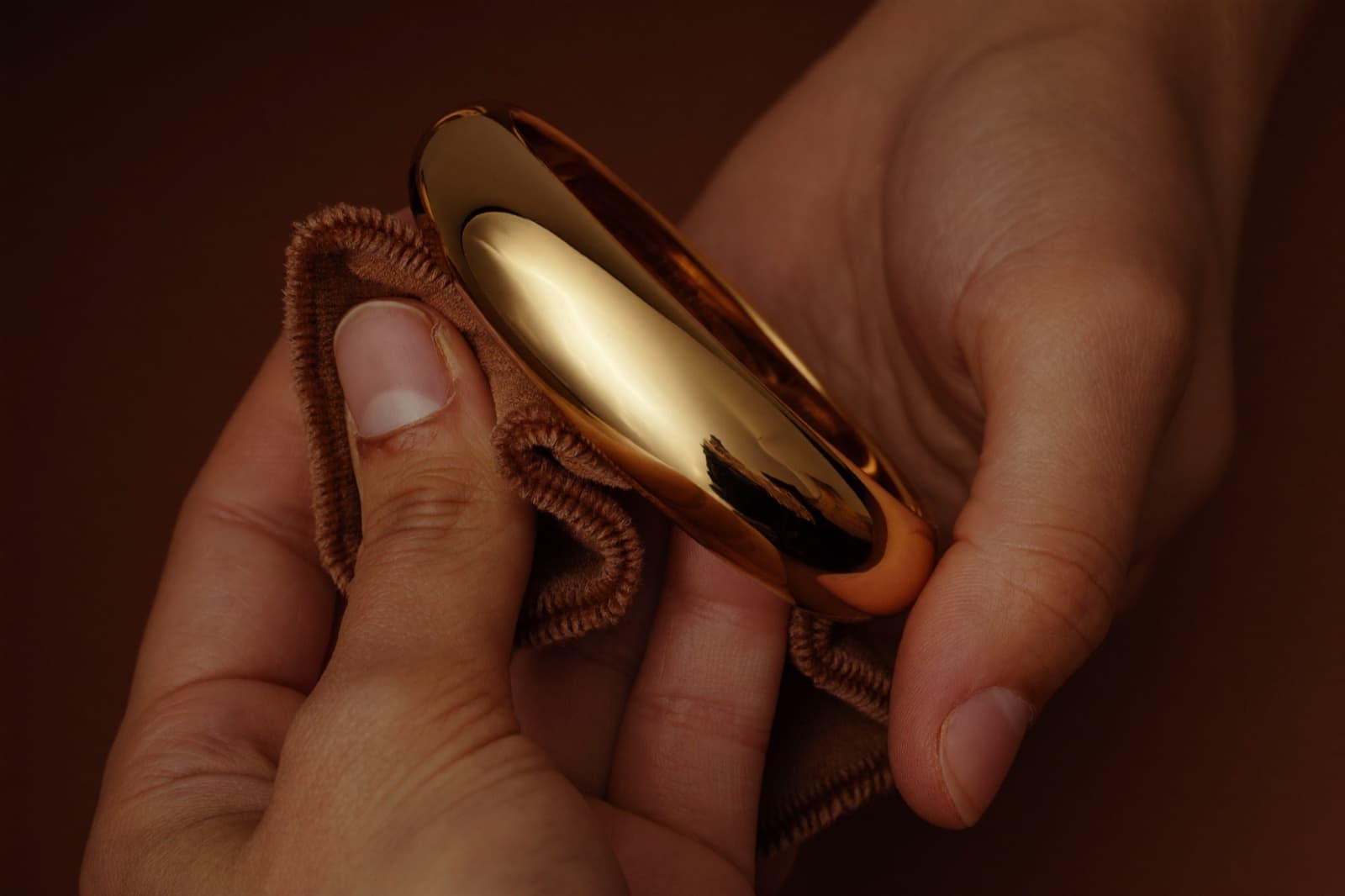Tangan menggilap gelang emas dengan kain lembut